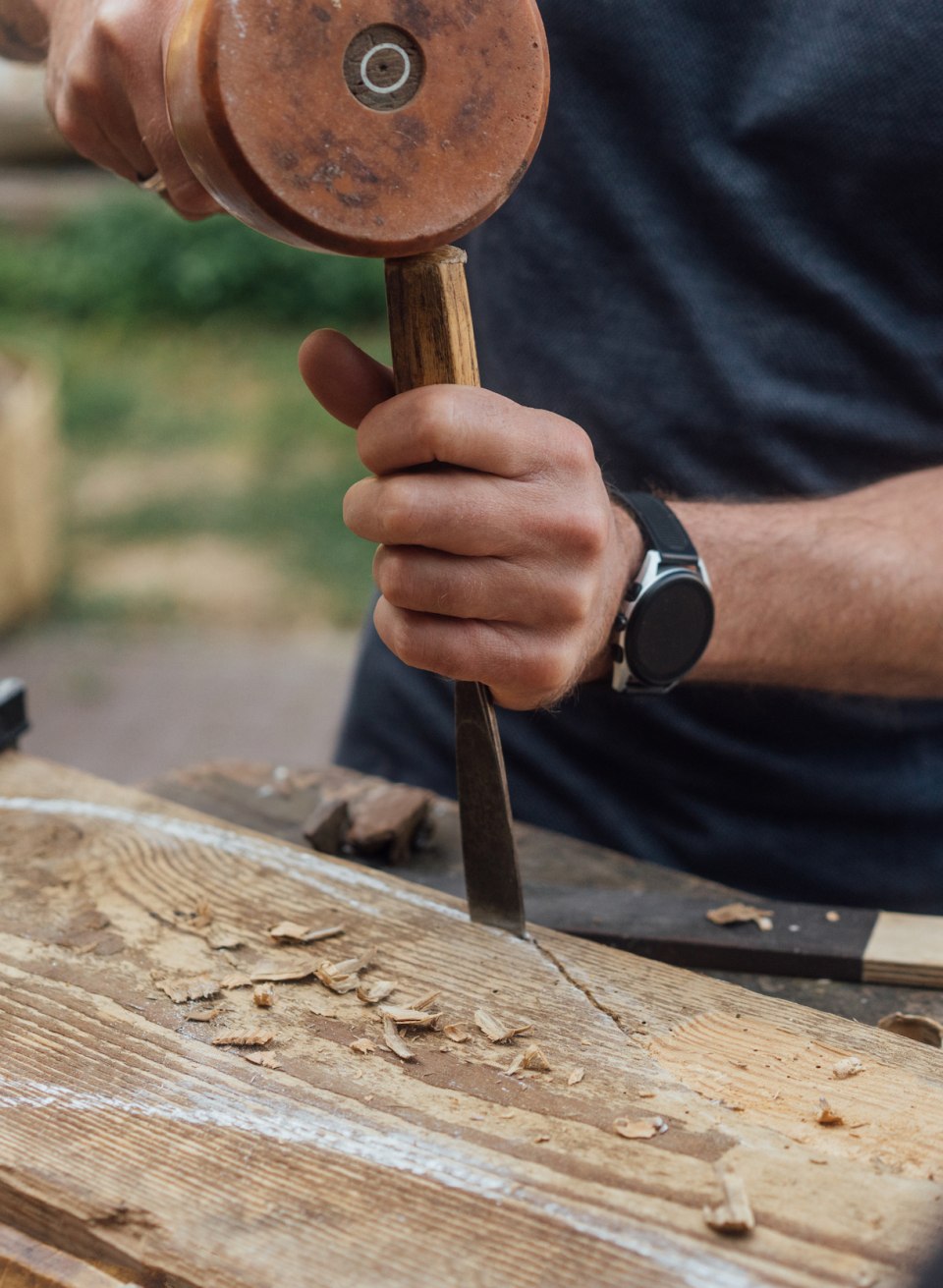 Fingerspitzengefühl: Andreas formt mit Klöppel und Meißel auf der Oberfläche des alten Holzstücks einen Fisch beim Bildhauer-Workshop., © TMV/Petermann