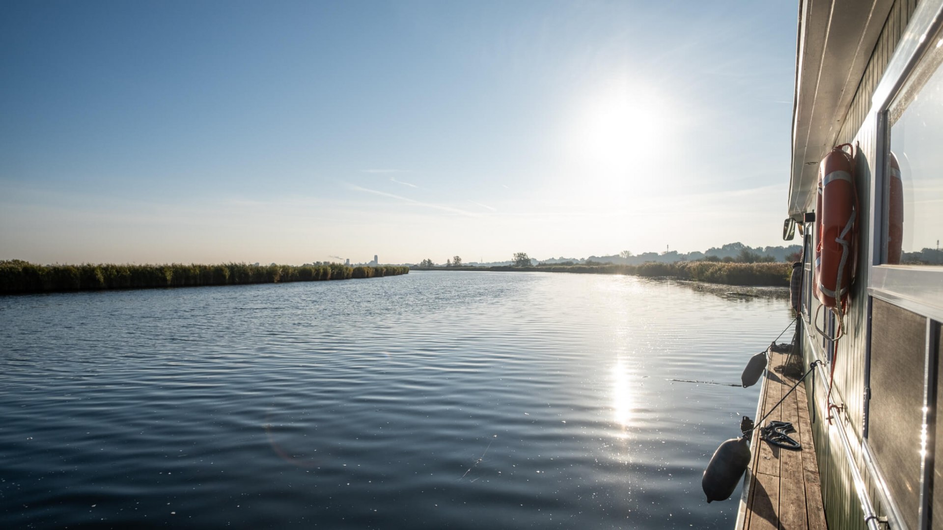 Hausboot auf der Peene bei strahlendem Sonnenschein und ruhigem Wasser in Richtung Anklam.