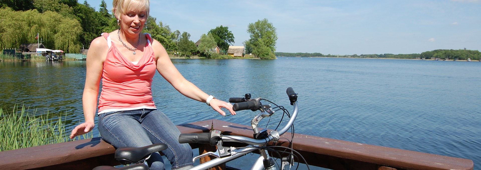 Eine Radfahrerin sitzt auf Geländer am See., © Ralf Tetmeyer, radreisen-mecklenburg