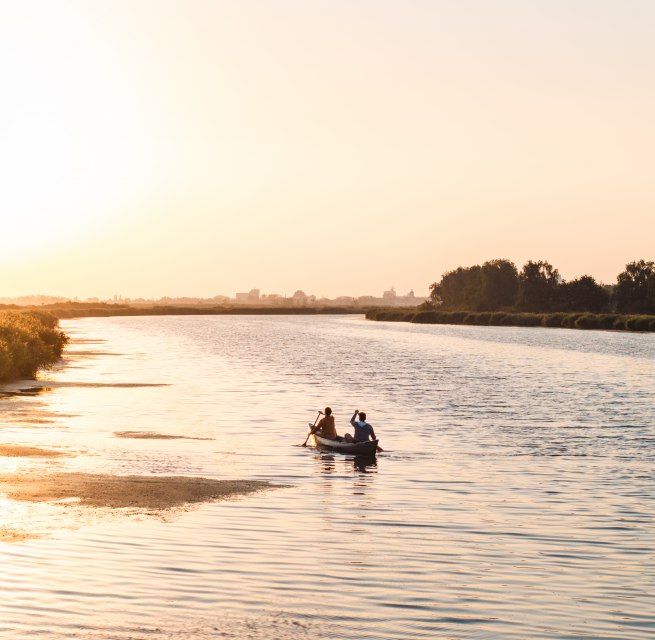 Ein ruhiger Abend auf dem Wasser: Zwei Personen paddeln bei Sonnenuntergang durch die weiten Gewässer Vorpommerns, umgeben von Natur und Stille.