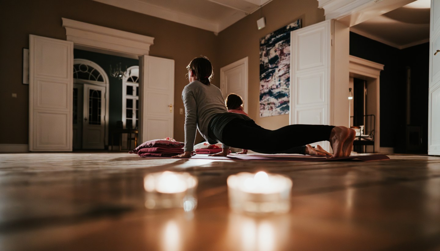 Yoga in der entspannten Atmosphäre des Gutshauses Pohnstorf – Ruhe und Achtsamkeit im Einklang mit historischem Ambiente und gemütlichem Kerzenlicht.