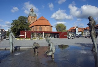 Marktplatz Ribnitz mit Brunnen "Der Bernsteinfischer" von Thomas Jastram, im Hintergrund Bernsteinhaus mit Tourist-Information und Stadtkirche St. Marien, © Stadt RDG, Amt für Tourismus, Schule und Kultur