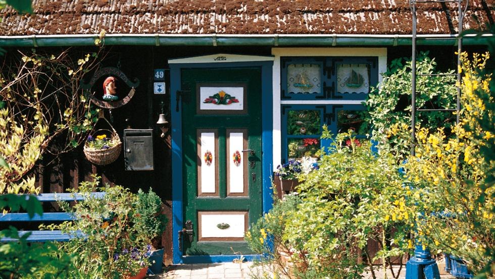 Mit Schnitzereien reich verzierte und bunt bemalte Haustür einer Fischerkate auf Fischland-Darß-Zingst, © TMV/Legrand