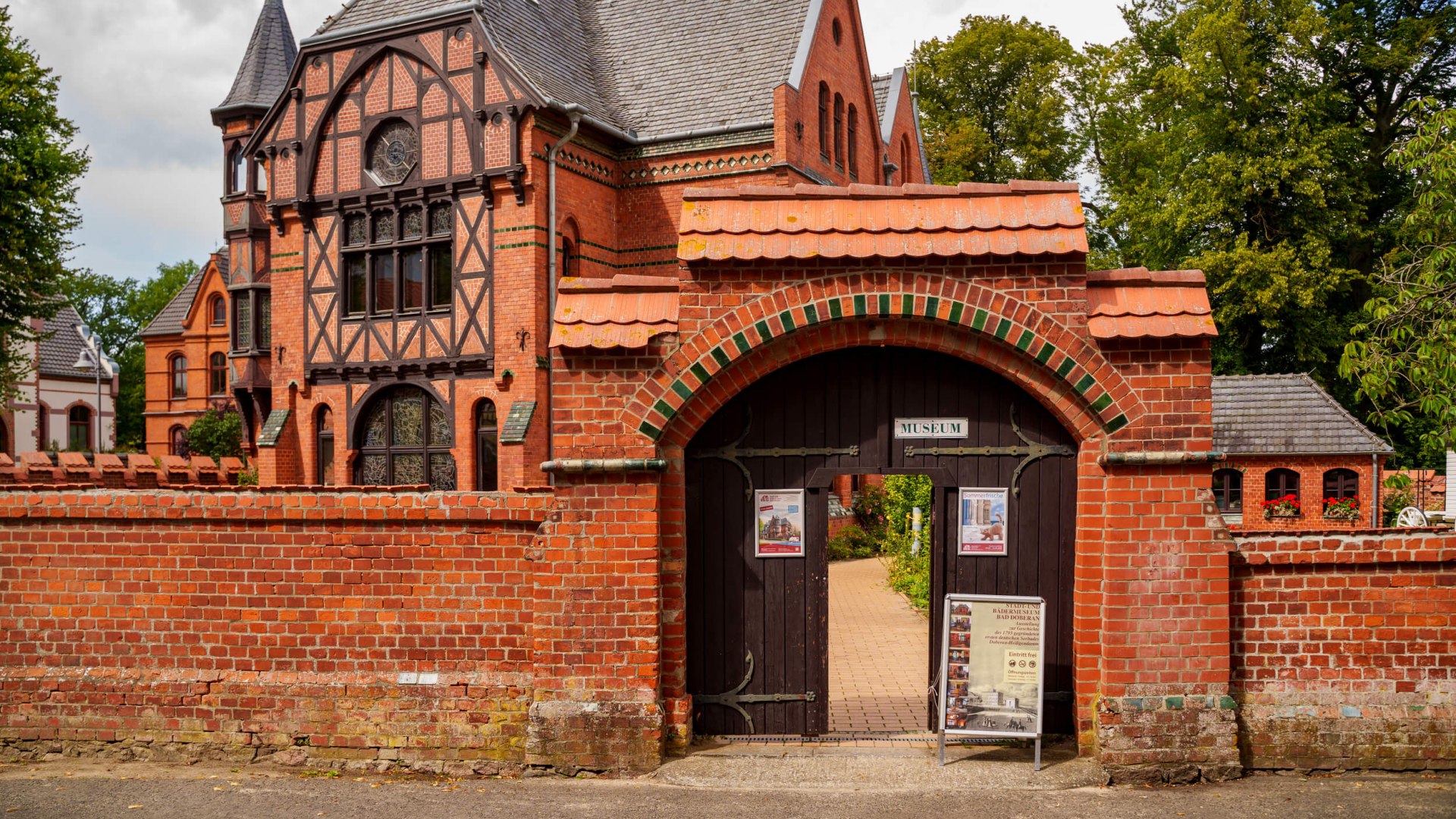 Das Stadt- und Bädermuseum im Möckelhaus in Bad Doberan, ein historisches Gebäude mit markanter Backstein- und Fachwerkarchitektur, umgeben von einer roten Backsteinmauer.