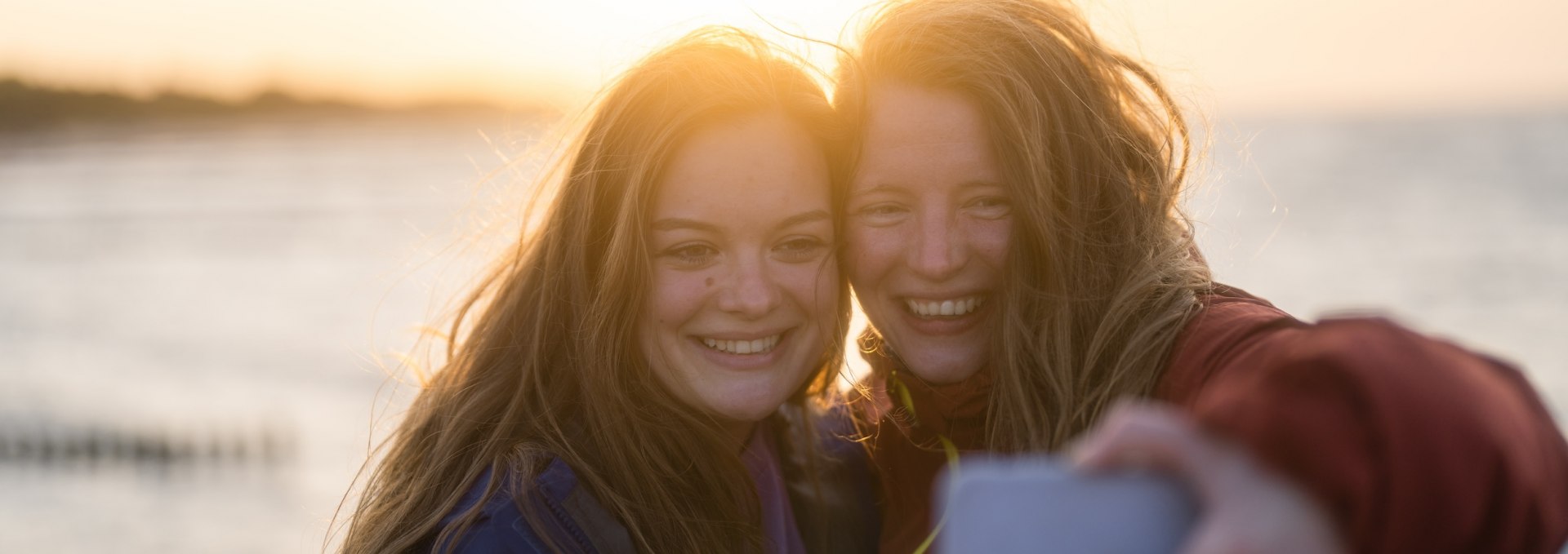 Ein windiges Selfie zum Abschluss muss sein! Man sieht Linda und Marie ihre Wanderfreude buchstäblich ins Gesicht geschrieben. Zum Sonnenuntergang beenden die beiden Wanderinnern ihre Tour auf dem Naturparkweg auf der Seebrücke in Koserow.  , © TMV/Gross