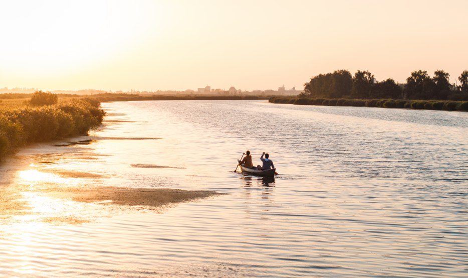 Ein ruhiger Abend auf dem Wasser: Zwei Personen paddeln bei Sonnenuntergang durch die weiten Gewässer Vorpommerns, umgeben von Natur und Stille.