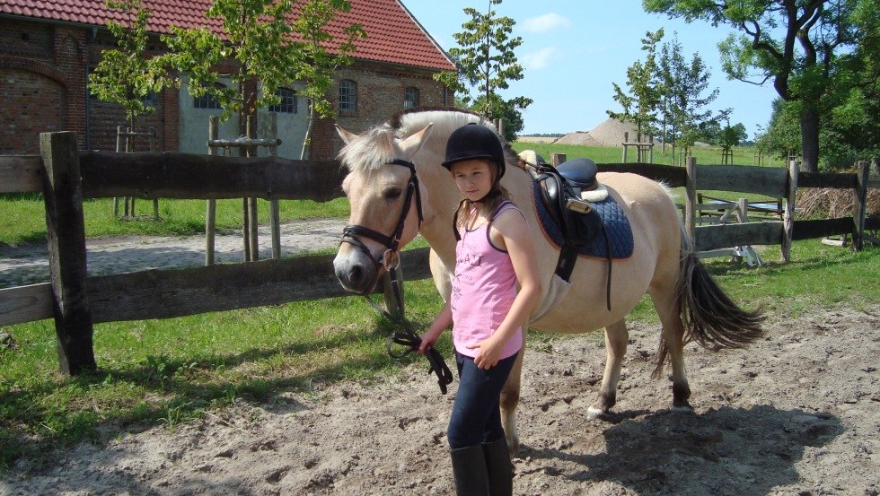 Im Sommer wird auf dem großen Reitplatz mit Sprüngen oder im Gelände geritten, im Winter nutzen wir die moderne große Reithalle, die eine Zuschauertribüne hat. Dann können Mami und Papi stolz zuschauen wie ihr Sprössling Fortschritte macht., © Reit- und Fahrverein Obermützkow e.V.