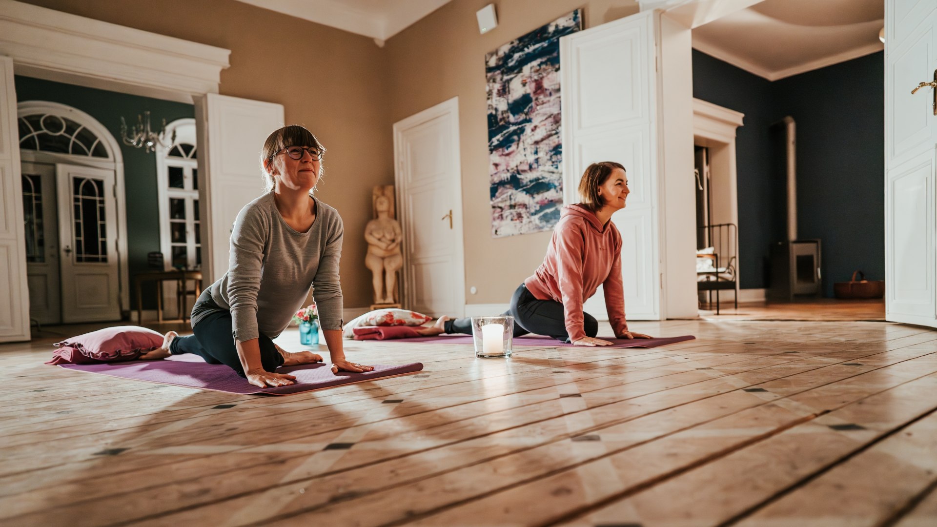 Zwei Teilnehmerinnen genießen eine Yoga-Session im Gutshaus Pohnstorf – Achtsamkeit und Bewegung in stilvoller und entspannter Umgebung.