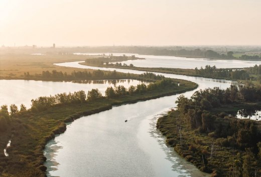 Ein Paar paddelt gemeinsam in einem Kanu über den Fluss die Peene in Mecklenburg-Vorpommern. Das Bild zeigt die Weite der Urlaubsregion Vorpommern.