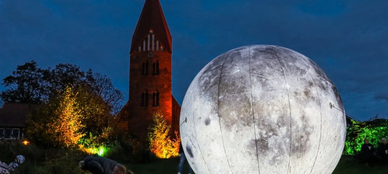 Leuchtender Mond im Stadtgarten Klütz - im Hintergrund die angestrahlte St. Marienkirche, © Helmut Strauß