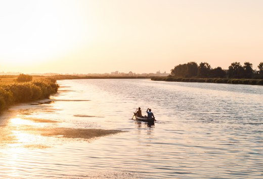 Ein ruhiger Abend auf dem Wasser: Zwei Personen paddeln bei Sonnenuntergang durch die weiten Gewässer Vorpommerns, umgeben von Natur und Stille.