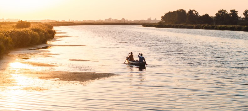 Ein ruhiger Abend auf dem Wasser: Zwei Personen paddeln bei Sonnenuntergang durch die weiten Gewässer Vorpommerns, umgeben von Natur und Stille.