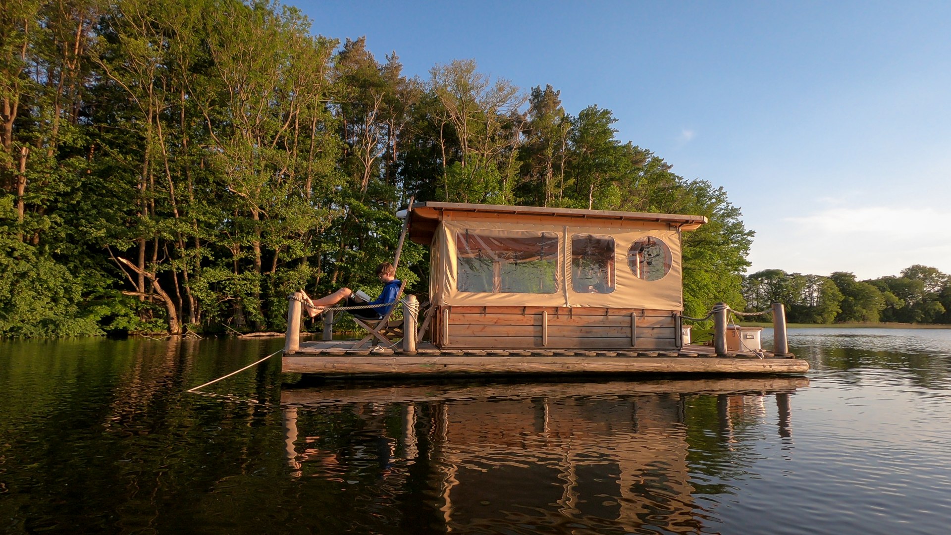 Gemächlich gleitet ein Floß über das Wasser, leise und dicht am Ufer entlang. Es ist Bade- und Angelbasis, Sonnendeck, Naturbeobachtungsstation sowie Ferienhaus in einem. Und das Tolle: Hier in der Mecklenburgischen Seenplatte gibt es genügend Seen, so dass jeder einen führerscheinfreien Floßurlaub genießen kann. Also dann: Leinen los!, © TMV/Myroad.de