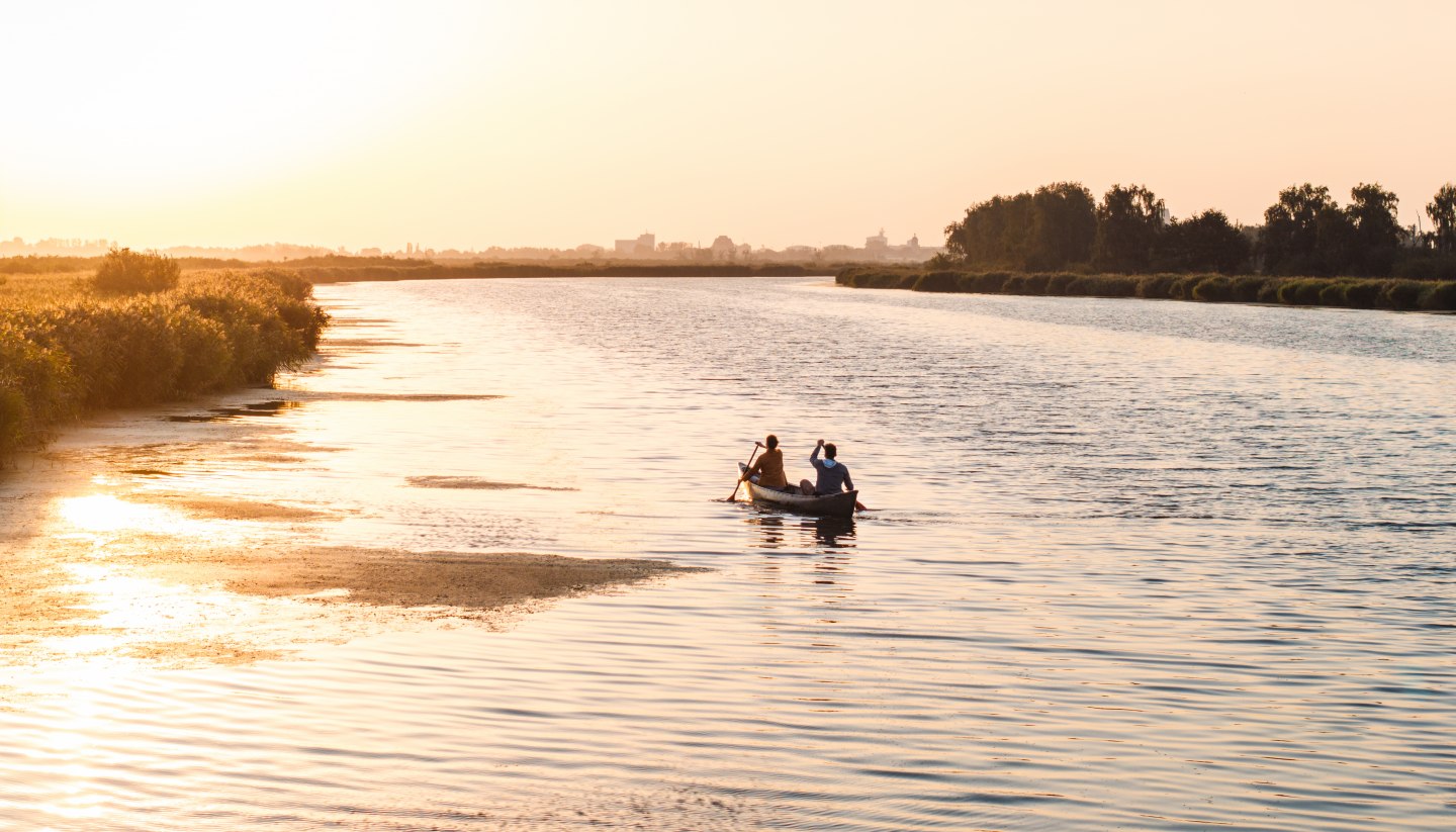 Ein ruhiger Abend auf dem Wasser: Zwei Personen paddeln bei Sonnenuntergang durch die weiten Gewässer Vorpommerns, umgeben von Natur und Stille.