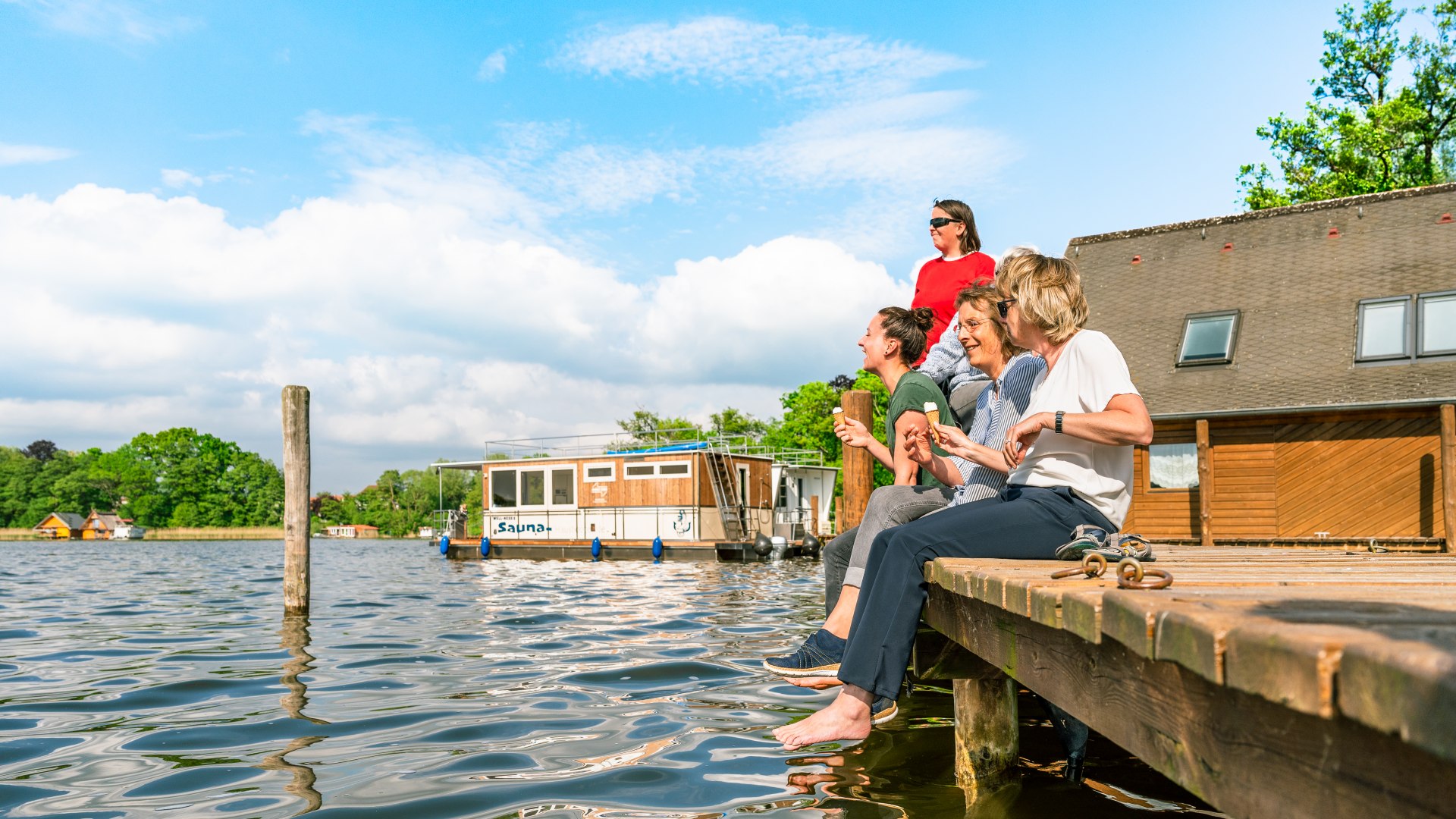 Auf dem Steg vor Schloss Mirow lässt es sich gut schnacken. Das Hausboot im Hintergrund ruht sich so lange ein bisschen aus., © TMV/Tiemann