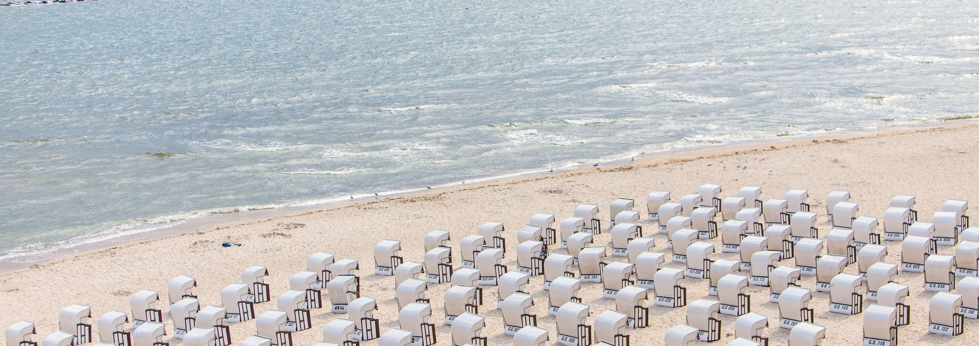 Wie kleine Miniaturfiguren reihen sich weiße Strandkörbe am Selliner Strand aneinander., © TMV/Krauss